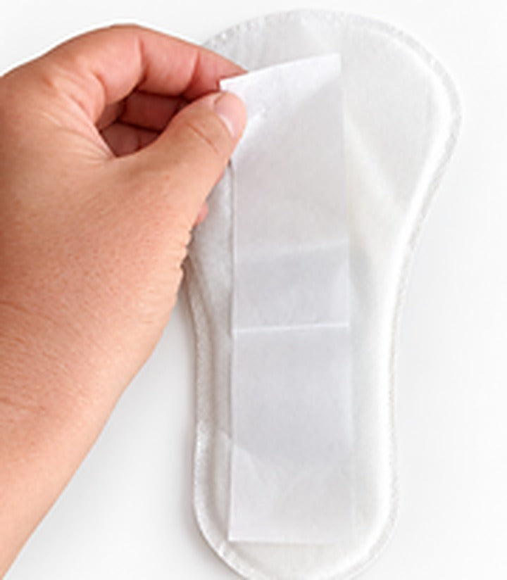 A hand peeling the release paper off the back of a UraGuard shield