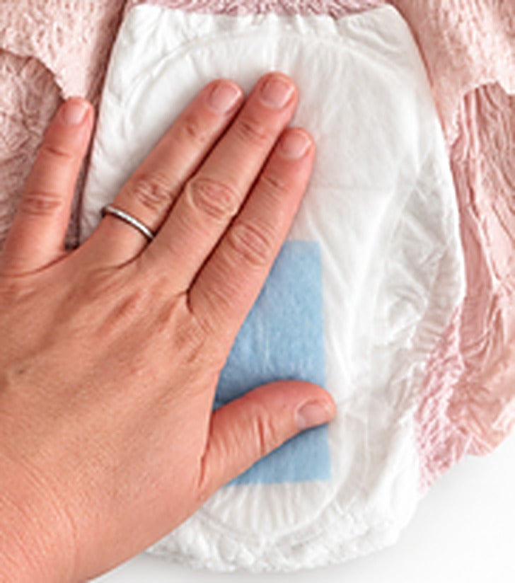 A hand gently pressing the shield flat inside the brief